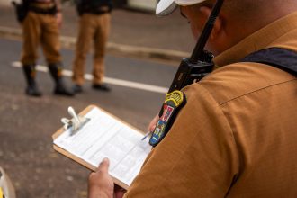 Policial registra informações em uma prancheta ao ar livre.