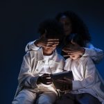 Mãe acompanha duas crianças durante o uso de um tablet, em contexto de supervisão e segurança digital.