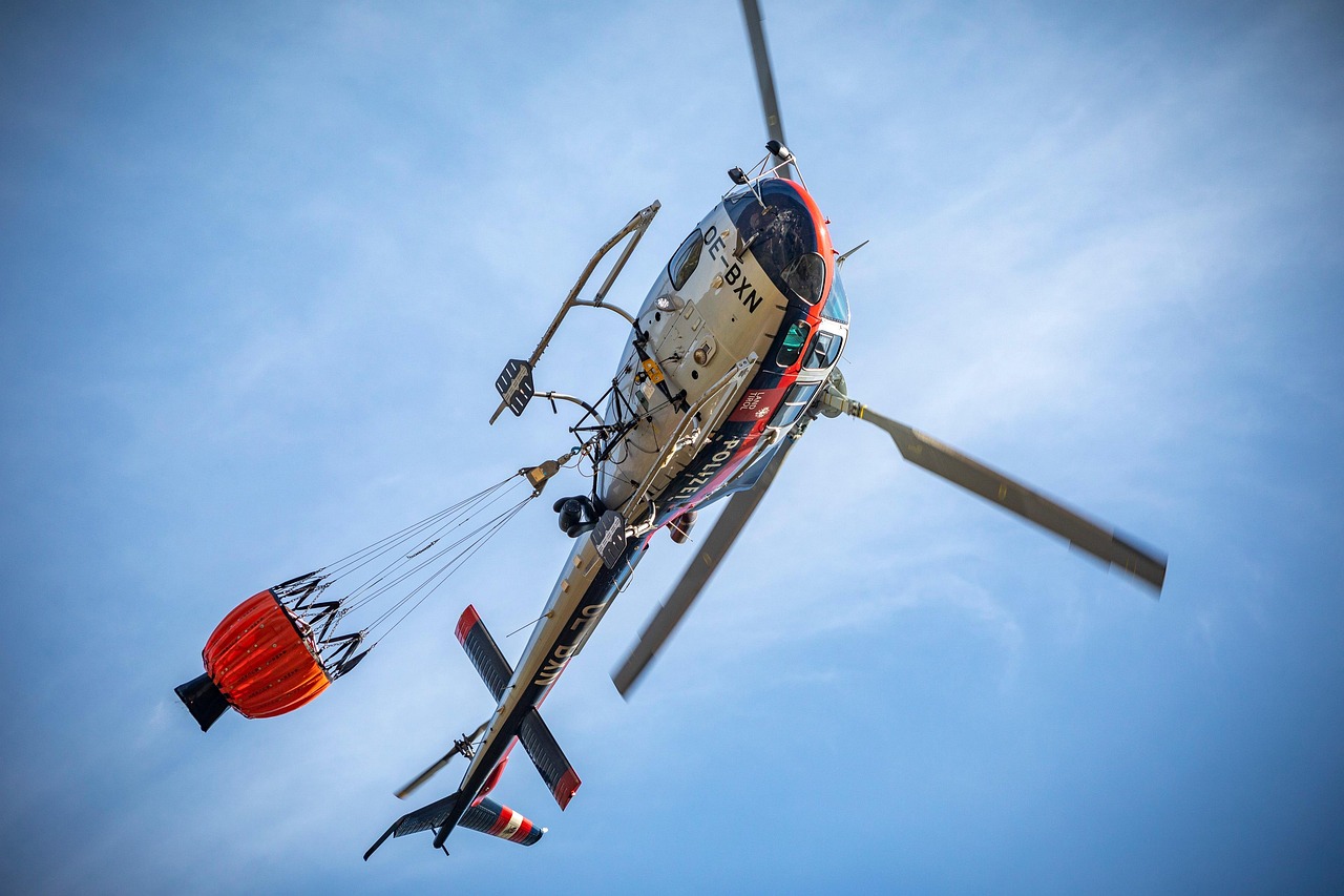Helicóptero equipado com bolsa de água sobrevoa uma área de floresta atingida por incêndio florestal